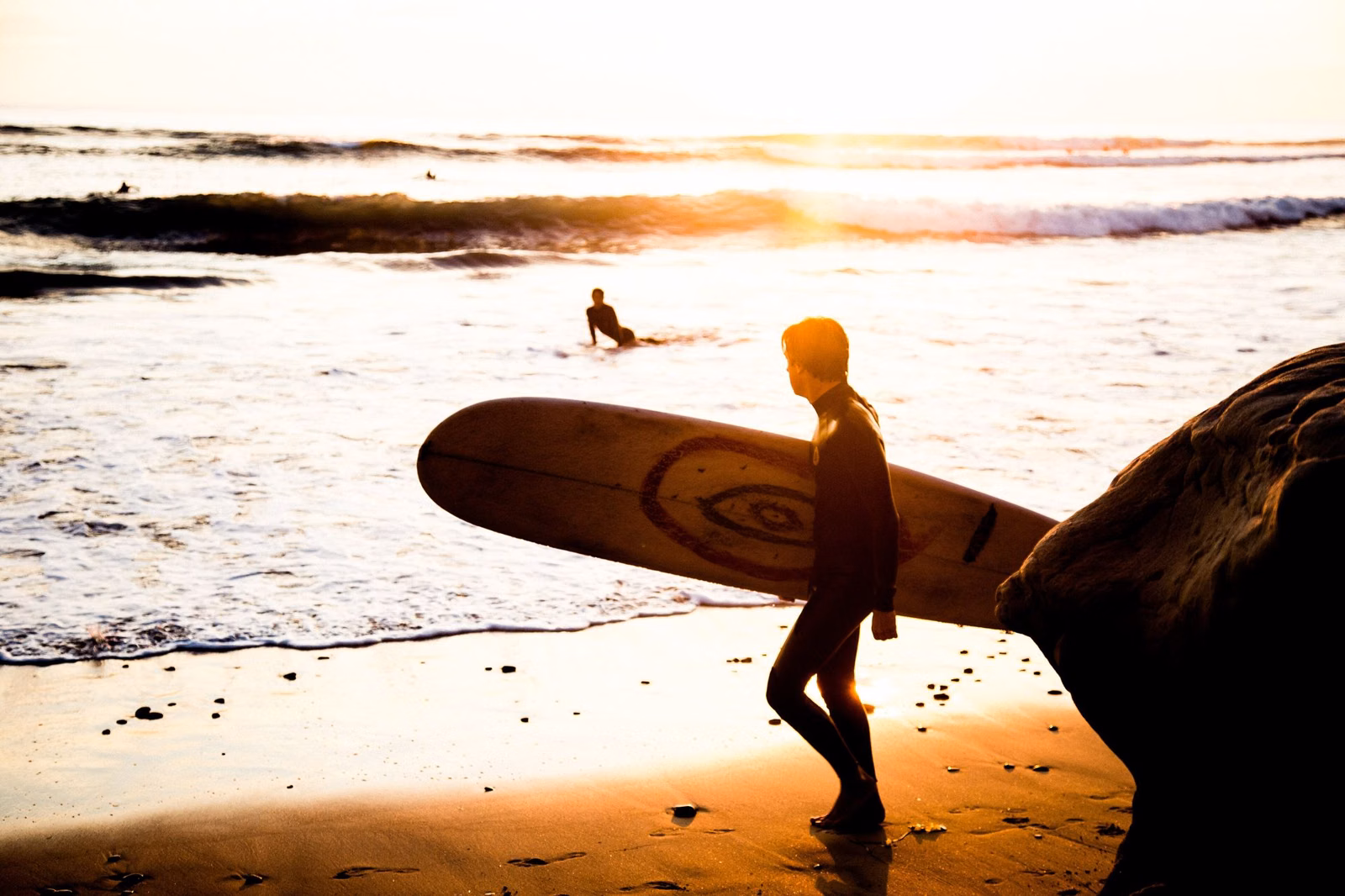 A surfer on the beach at golden hour